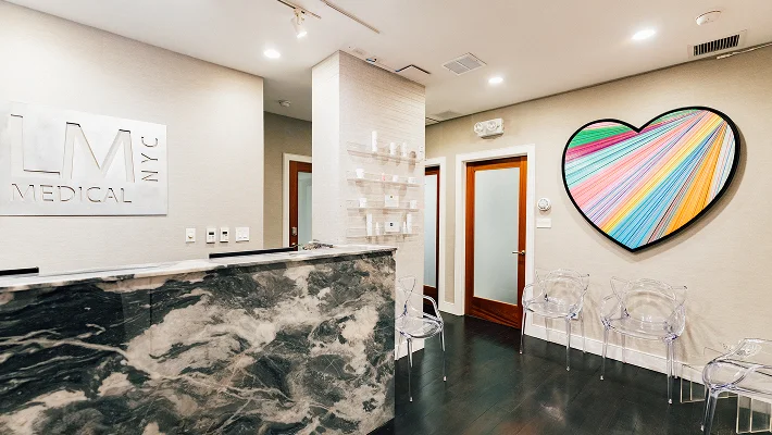 Modern medical office reception area with marble walls, glossy floor, and colorful heart artwork