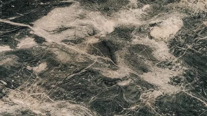 Aerial view of sand dunes with scattered vegetation and winding trails through coastal landscape