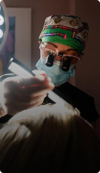 Surgeon in surgical mask and headlamp performing medical procedure with surgical instruments