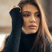 Woman in black turtleneck sweater with hand on head, long dark hair, natural makeup, indoor portrait