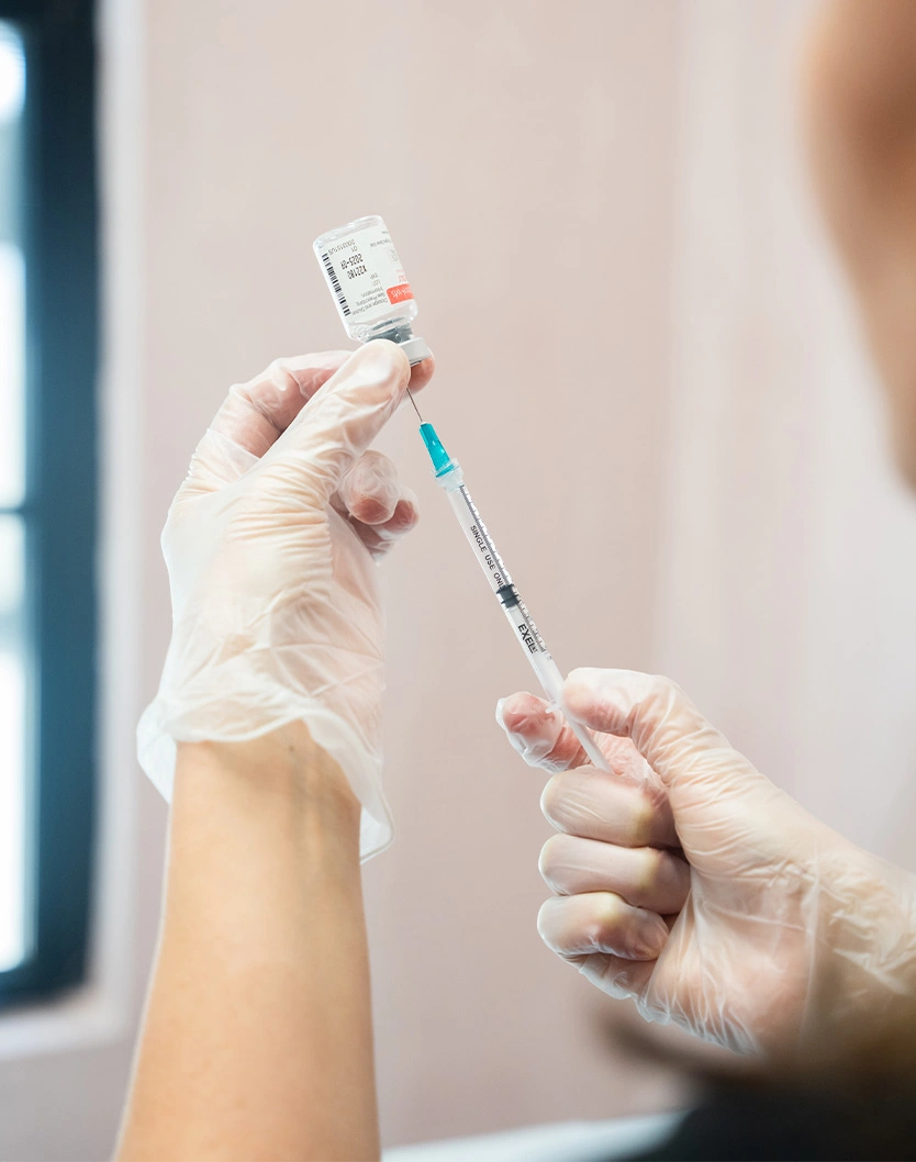 Healthcare worker preparing vaccine injection with syringe in medical gloves for patient immunization