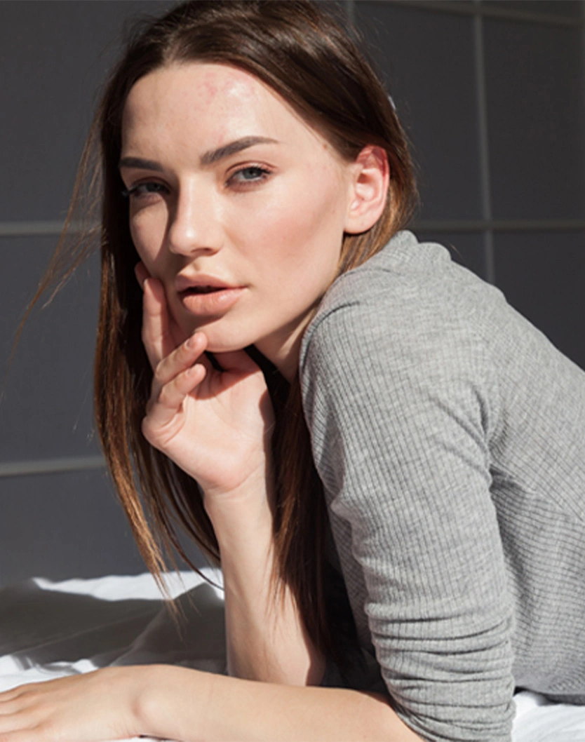Woman in gray turtleneck sweater with hand on chin posing for beauty portrait photograph