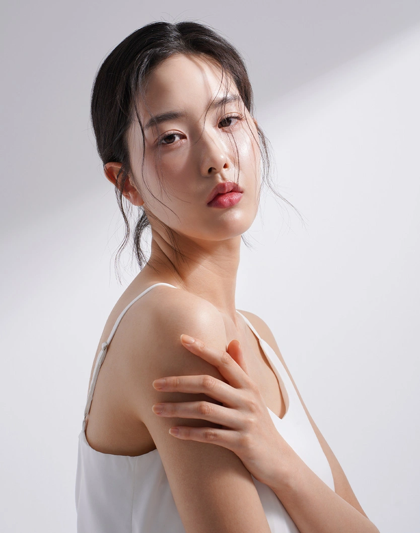Young Asian woman with natural makeup touching shoulder on white background skincare concept
