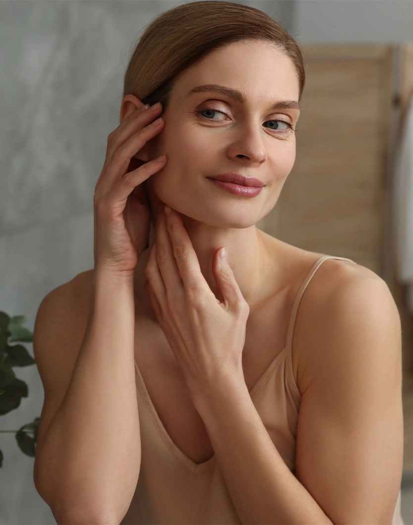 Woman with glowing skin touching face and neck in natural skincare beauty portrait