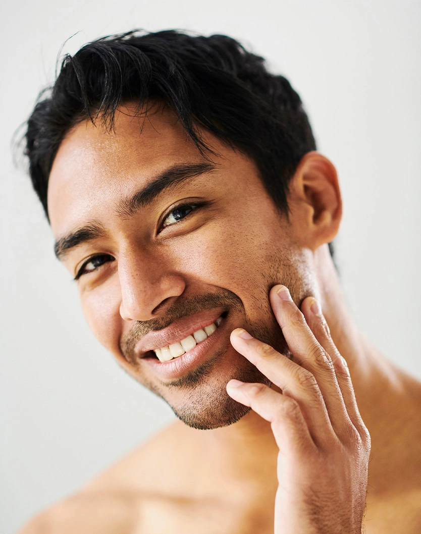 Smiling man with hand on face showing smooth skin after shaving or skincare routine